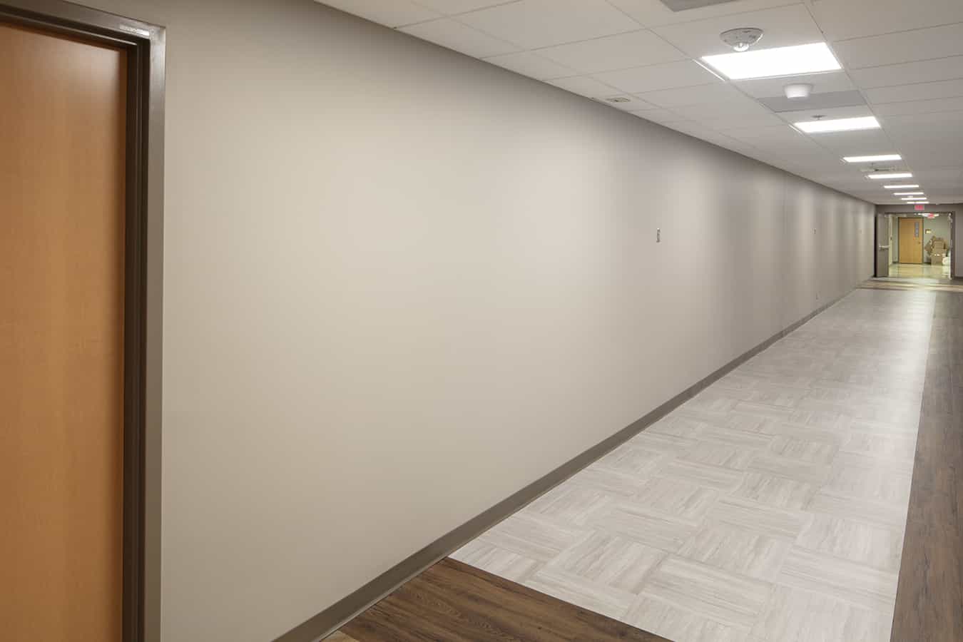 blank white wall in long corridor in basement of older healthcare facility 